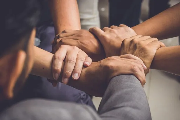 Community members holding hands in mutual support